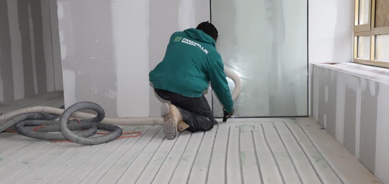 Monteur legt vloerverwarmingsbuizen in gefreesde vloer